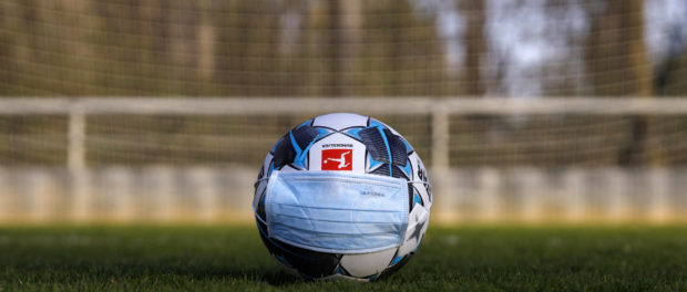 Der offizielle Spielball der Bundesliga Derbystar liegt mit Mundschutz auf einem Fußballplatz. Köln, 11.04.2020 *** The